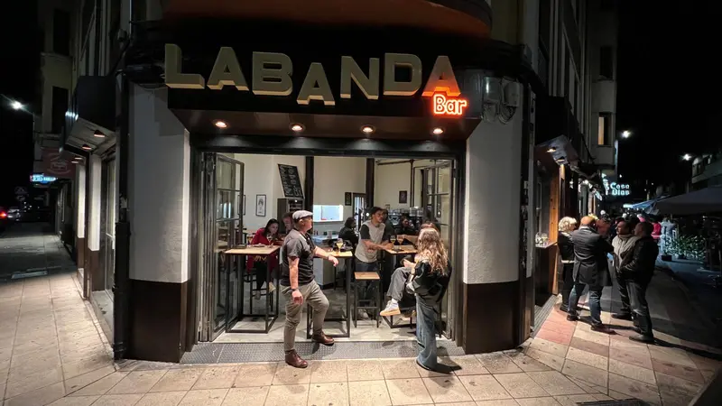 Corner bar storefront at night with people outside